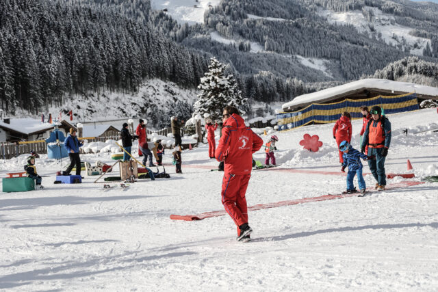 Skifahrer und Kinder auf einem verschneiten Hang