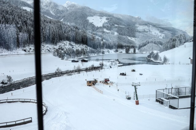 Winterlandschaft mit Schnee, Bäumen und Wasser.