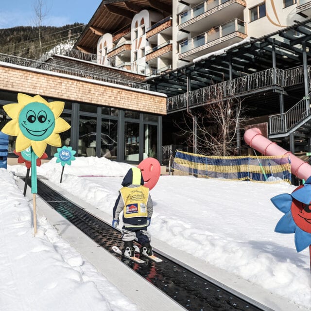 Kind fährt Ski in verschneiter Umgebung mit Blumen