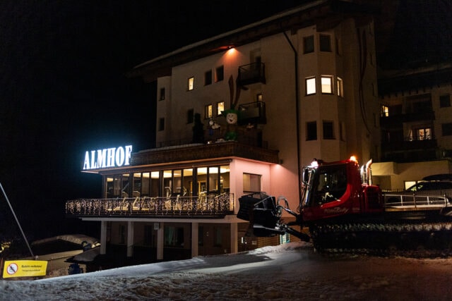 Hotel Almhof bei Nacht mit Pistenraupe