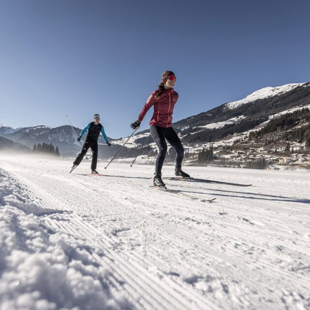 Zwei Menschen beim Skilanglauf im Schnee.